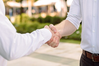 The image depicts two individuals shaking hands, likely as a greeting or agreement.