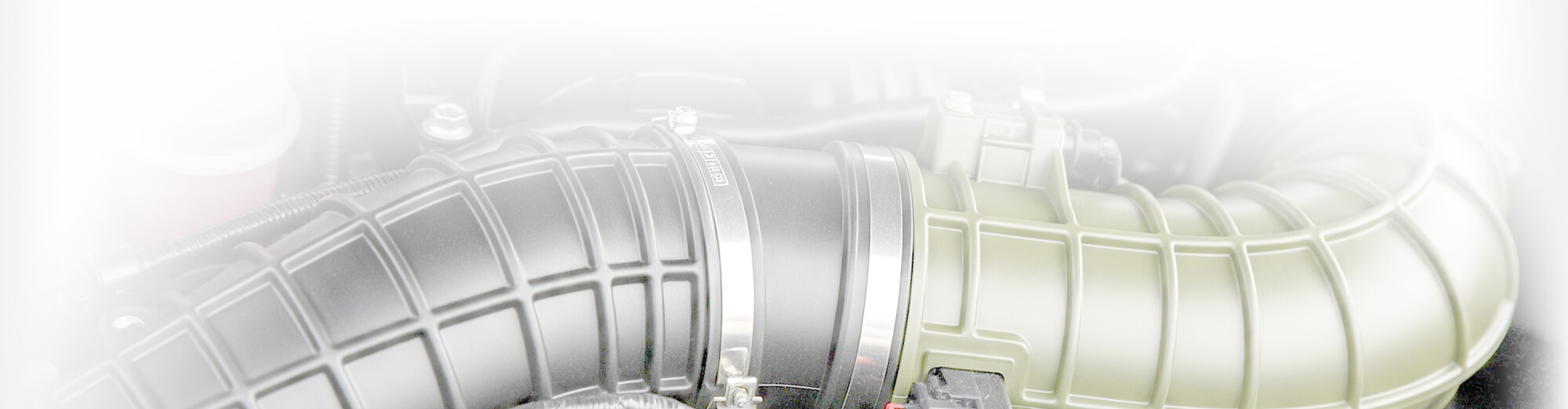 The image shows a close-up of a car's air intake system, featuring a large, curved pipe and associated fittings.